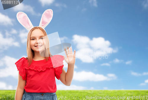 Image of happy girl wearing easter bunny ears waving hand