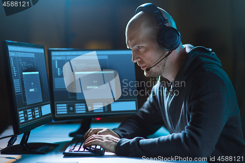 Image of hacker with computer and headset in dark room