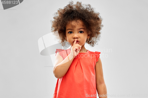 Image of little african american girl making shush gesture