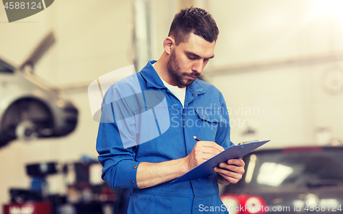 Image of auto mechanic man with clipboard at car workshop