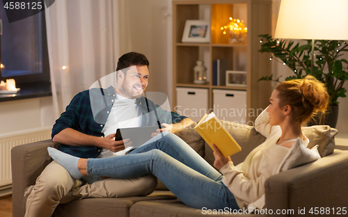 Image of couple with tablet computer and book at home