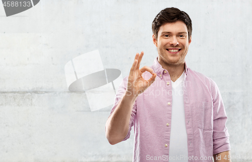 Image of smiling young man showing ok hand sign