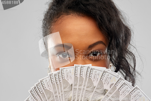 Image of african american woman hiding face behind money