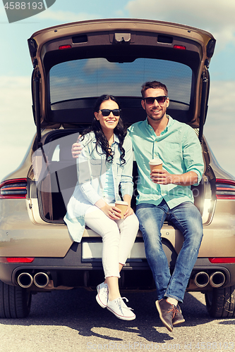 Image of happy couple with coffee at hatchback car trunk