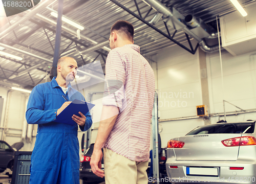 Image of auto mechanic with clipboard and man at car shop