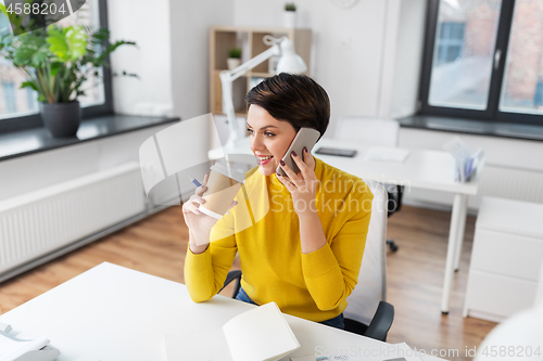 Image of businesswoman calling on smartphone at office