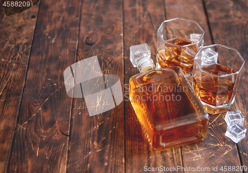 Image of Bottle of whiskey with two glasses placed on rustic wooden table