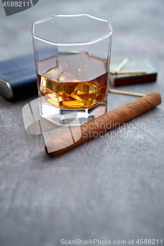 Image of Glass of whiskey with ice, big cuban cigar, matches and hip flask