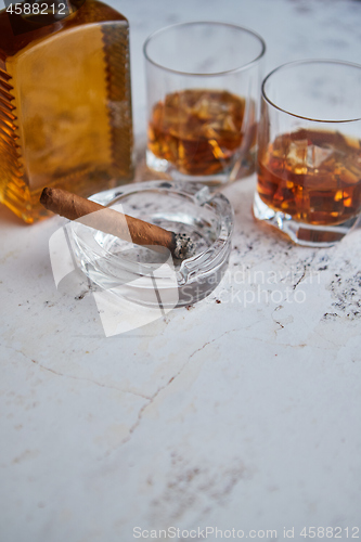 Image of Bottle and glasses of brandy or wiskey and nice big cuban cigar