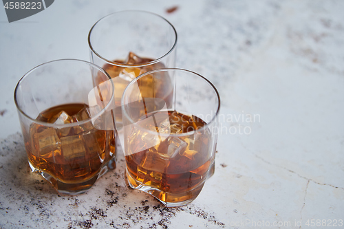 Image of Three glasses filled with ice cubes and old aromatic whiskey