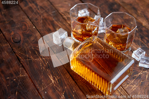 Image of Bottle of whiskey with two glasses placed on rustic wooden table