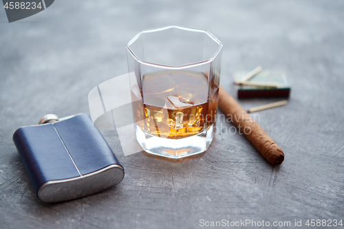 Image of Glass of whiskey with ice, big cuban cigar, matches and hip flask