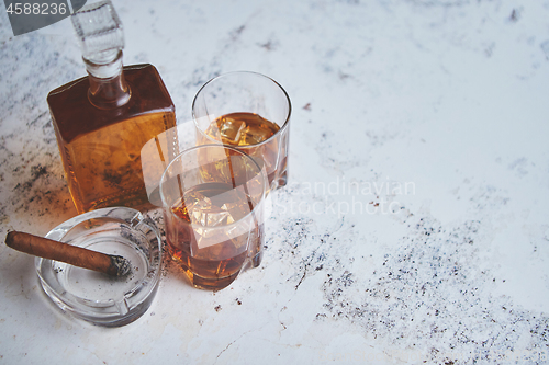 Image of Bottle and glasses of brandy or wiskey and nice big cuban cigar