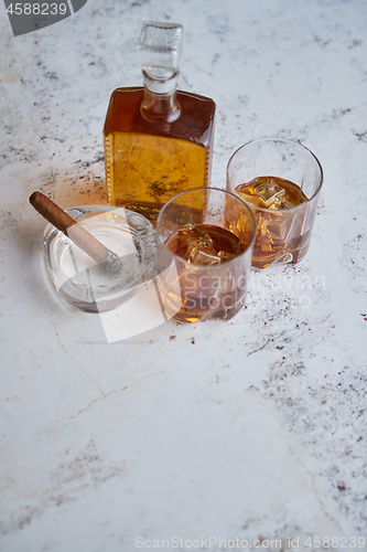 Image of Bottle and glasses of brandy or wiskey and nice big cuban cigar