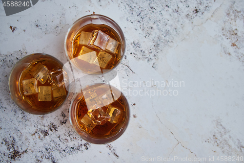 Image of Three glasses filled with ice cubes and old aromatic whiskey
