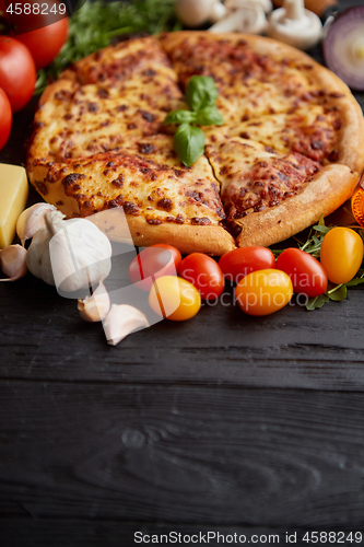 Image of Delicious italian pizza served on black wooden table