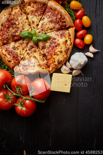 Image of Delicious italian pizza served on black wooden table