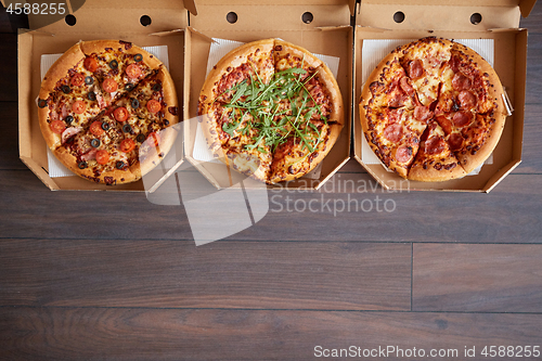 Image of Three different kind of pizzas in delivery boxes