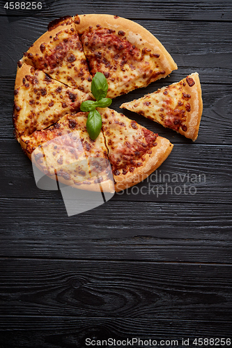 Image of Sliced pizza Margarita with basil leafs