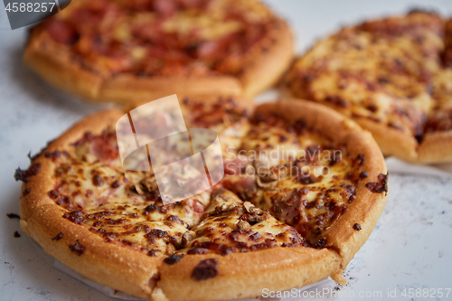 Image of Three american style pizzas served on a table