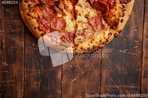 Image of Fluffy pepperoni pizza in american style placed on rusty old wooden table