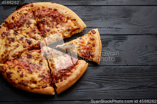 Image of Fluffy pepperoni pizza in american style placed on rusty old black wooden table