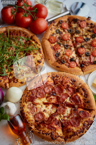 Image of Three american style pizzas served on a table