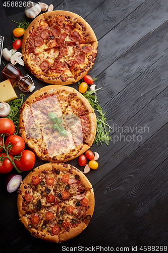 Image of Freshly served, three various pizzas placed among tasty ingredie