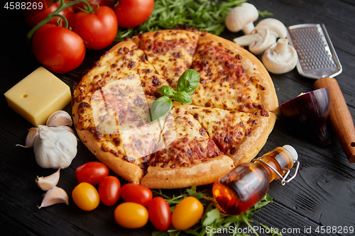 Image of Delicious italian pizza served on black wooden table