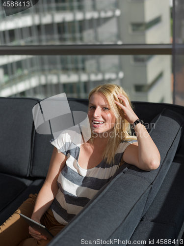 Image of young woman on sofa at home surfing web