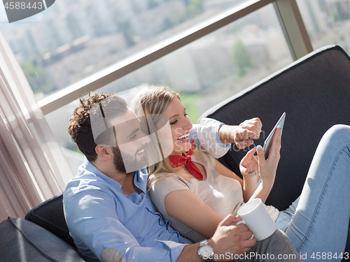 Image of couple relaxing at  home with tablet computers