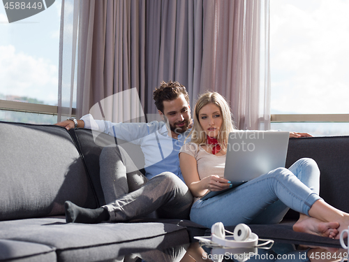 Image of couple relaxing at  home using laptop computer