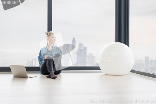 Image of woman drinking coffee and using laptop at home