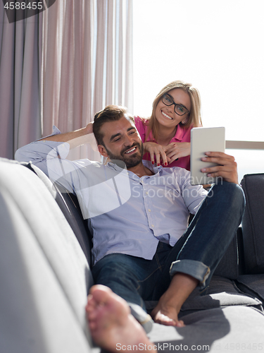 Image of couple relaxing at  home with tablet computers