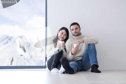 Image of multiethnic couple enjoying morning coffee by the window