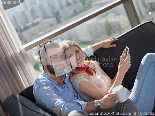 Image of couple relaxing at  home with tablet computers