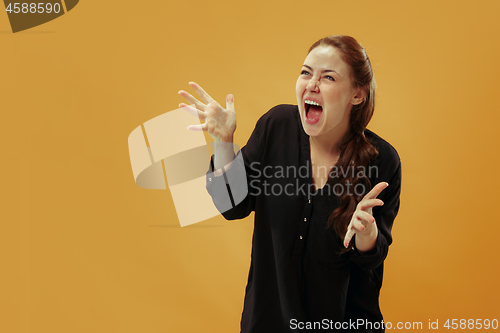 Image of The young emotional angry woman screaming on gold studio background