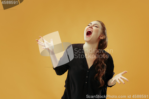 Image of The young emotional angry woman screaming on gold studio background