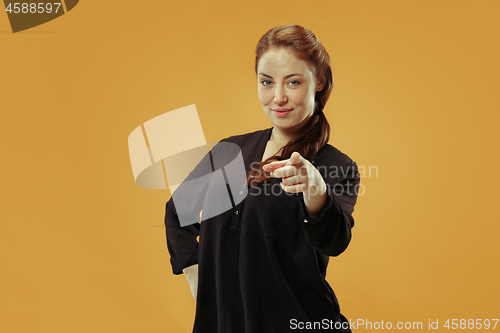 Image of The happy business woman point you and want you, half length closeup portrait on gold background.