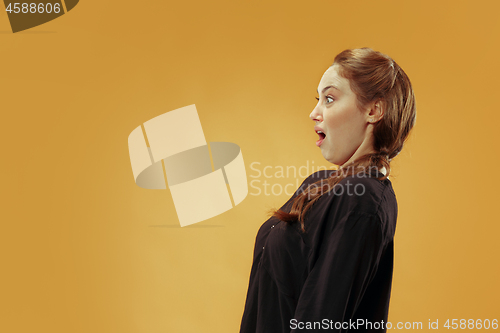 Image of Beautiful woman looking suprised and bewildered isolated on gold