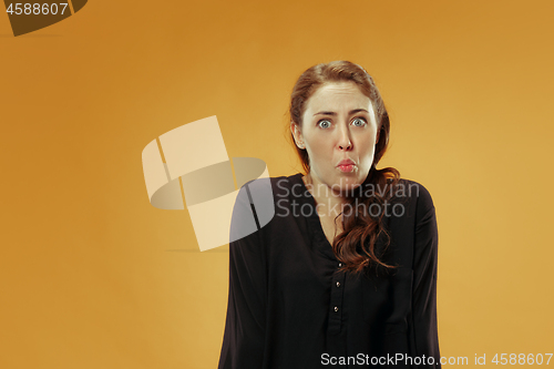 Image of Beautiful woman looking suprised and bewildered isolated on gold
