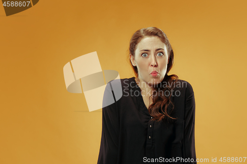 Image of Beautiful woman looking suprised and bewildered isolated on gold