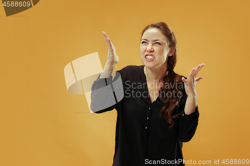 Image of Beautiful female half-length portrait isolated on gold studio backgroud. The young emotional surprised woman