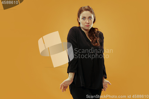 Image of Beautiful woman looking suprised and bewildered isolated on gold