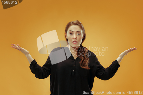 Image of Beautiful female half-length portrait isolated on gold studio backgroud. The young emotional surprised woman
