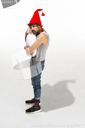 Image of Vertical shot of a content young man hugging a white pillow