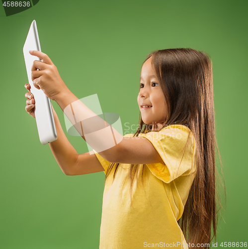 Image of Teen girl with laptop. Love to computer concept. Attractive female half-length front portrait, trendy green studio backgroud.