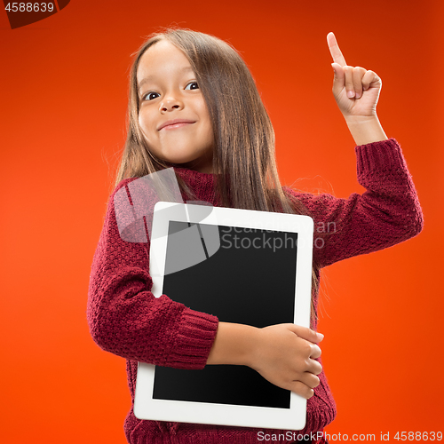 Image of Little funny girl with tablet on studio background