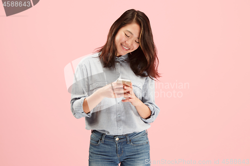 Image of Young beautiful woman using mobile phone studio on pink color background