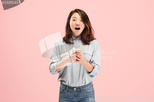 Image of Young beautiful woman using mobile phone studio on pink color background